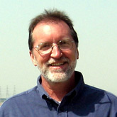 A headshot of Dr. Terry Baxter - a smiling older white male with wireframe glasses and a beard.